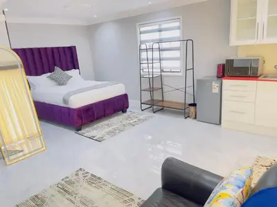 a living room with a bed and a kitchen at The Airport Terminal Guesthouse in Kempton Park