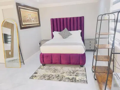 a bedroom with a bed with a red headboard and a ladder at The Airport Terminal Guesthouse in Kempton Park