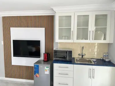 a kitchen with a sink and a microwave and a refrigerator at The Airport Terminal Guesthouse in Kempton Park