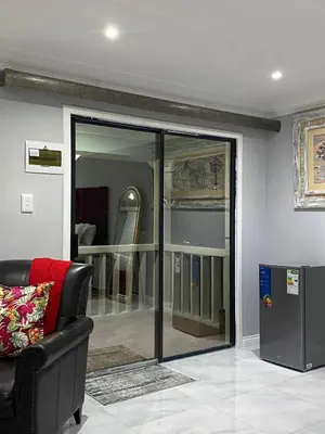 a living room with a sliding glass door with a chair at The Airport Terminal Guesthouse in Kempton Park
