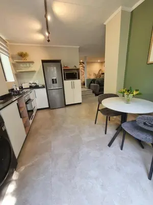 a kitchen and living room with a table and chairs at Edward suites ,Apartment 2 in Pretoria