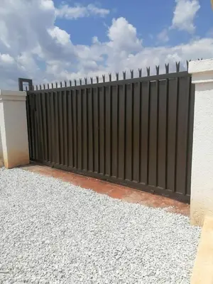 a black fence in front of a house at Dula Bonolo Lodge in Lebaleng