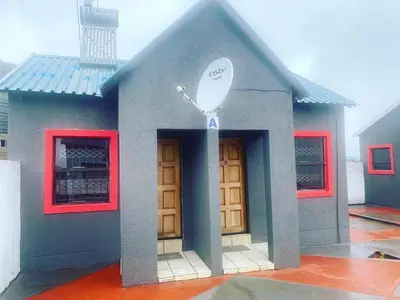a small blue house with red windows and a door at Dula Bonolo Lodge in Lebaleng
