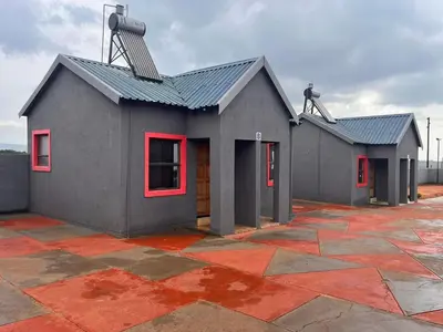 a gray house with red windows and a roof at Dula Bonolo Lodge in Lebaleng
