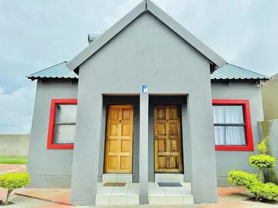 a small house with two wooden doors on it at Dula Bonolo Lodge in Lebaleng