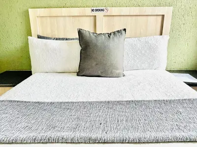 a bed with a white comforter and pillows at Dula Bonolo Lodge in Lebaleng