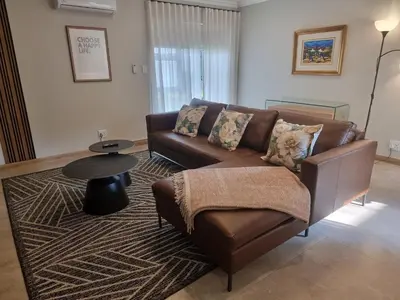 a living room with a brown couch and a table at Edward Suites, Apartment 1 in Pretoria