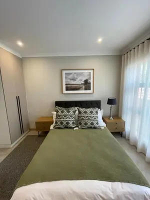 a bedroom with a large bed with a green blanket at Edward Suites, Apartment 1 in Pretoria