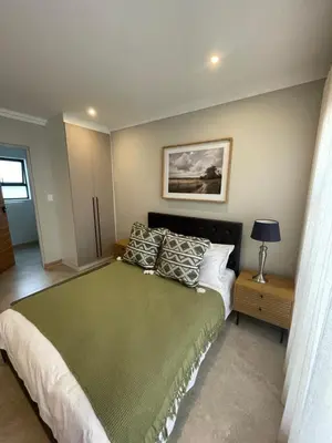 a bedroom with a large green bed with pillows at Edward Suites, Apartment 1 in Pretoria