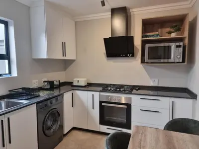 a kitchen with a stove and a sink and a microwave at Edward Suites, Apartment 1 in Pretoria