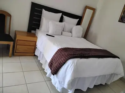a bedroom with a large white bed with a wooden headboard at Best Enough Guesthouse in Pretoria