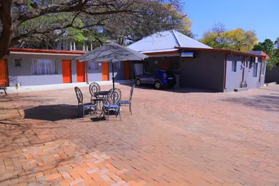 a table and chairs with an umbrella in a courtyard at Best Enough Guesthouse in Pretoria