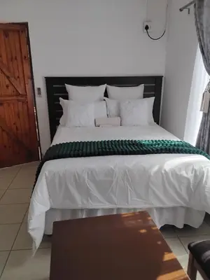 a bedroom with a large white bed and a wooden door at Best Enough Guesthouse in Pretoria