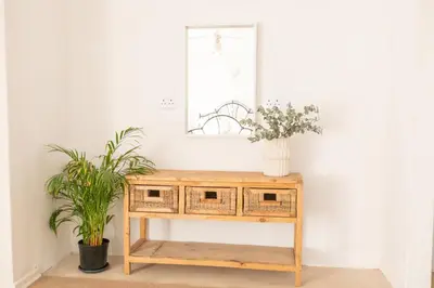 a wooden console table with a mirror and two plants at 28 Schalk drive in Polokwane