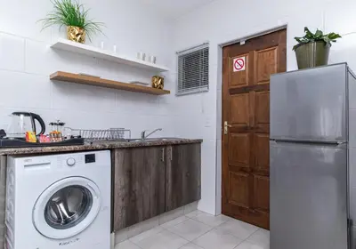 a kitchen with a washing machine and a refrigerator at Willow House Oasis - Your Haven in Kempton Park