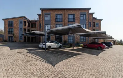 a parking lot with cars and umbrellas in front of a building at Willow House Oasis - Your Haven in Kempton Park
