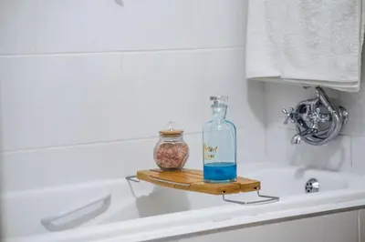 a bottle and a vase on a tray on a bath tub at Willow House Oasis - Your Haven in Kempton Park