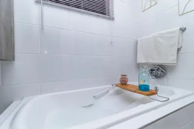 a bathroom with a bath tub with a bottle on a shelf at Willow House Oasis - Your Haven in Kempton Park