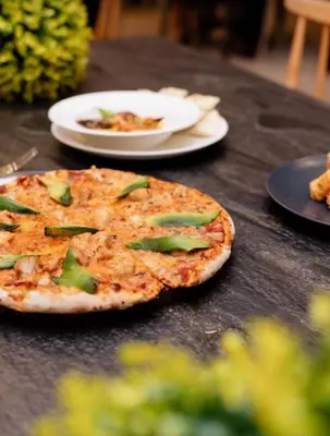 a pizza sitting on a table with plates of food at The Blyde blue lagoon in Pretoria