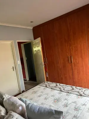 an empty bedroom with a bed and wooden cabinets at Nzwaki Self Catering in Nelspruit