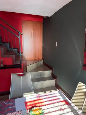 a living room with stairs and a table and chairs at Nzwaki Self Catering in Nelspruit