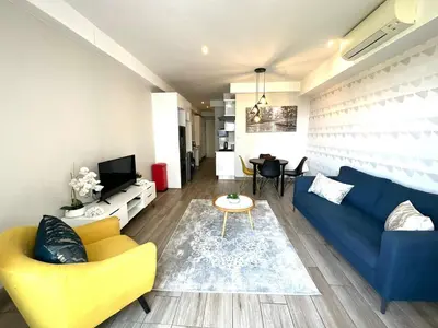 a living room with a blue couch and yellow chairs at Stay Menlyn - Luxe Apartment 617 in Pretoria