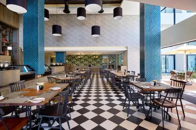 a restaurant with wooden tables and chairs and a checkered floor at Stay Menlyn - Luxe Apartment 617 in Pretoria