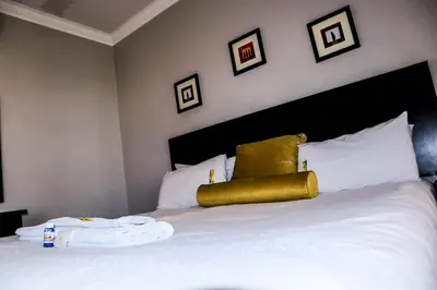 a bed with a gold pillow on top of it at Masai Shuttles And Hotel in Polokwane