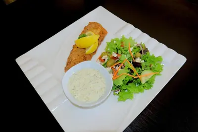 a white plate with a salad and a bowl of dip at Masai Shuttles And Hotel in Polokwane