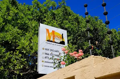 a sign on top of a wall with flowers at Masai Shuttles And Hotel in Polokwane