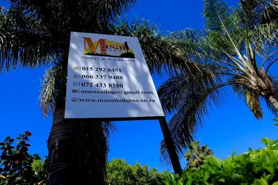 a sign on a tree with a palm tree at Masai Shuttles And Hotel in Polokwane