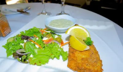 a plate of food with fish and salad on a table at Masai Shuttles And Hotel in Polokwane