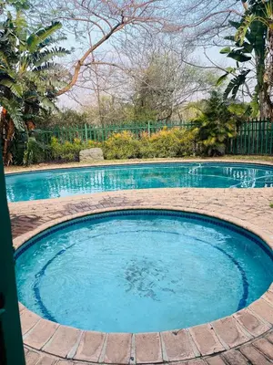 a large pool of blue water in a yard at Intsika apartments in Nelspruit