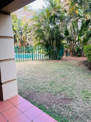 a view of a yard with a fence and palm trees at Intsika apartments in Nelspruit