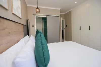 a bedroom with a large bed with white pillows at Unit 203 at Glen Park in Pretoria
