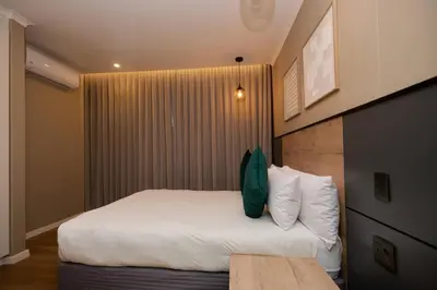 a bedroom with a bed with white sheets and pillows at Unit 203 at Glen Park in Pretoria