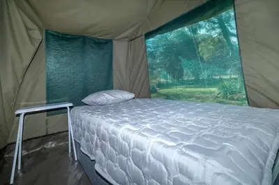 a white bed in a tent with a window at Die BosKamp - Hartbeespoort Dam in Hartbeespoort