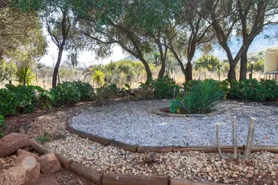 a garden with rocks and trees in the background at Die BosKamp - Hartbeespoort Dam in Hartbeespoort