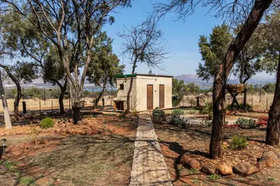 a small house in a field with trees at Die BosKamp - Hartbeespoort Dam in Hartbeespoort