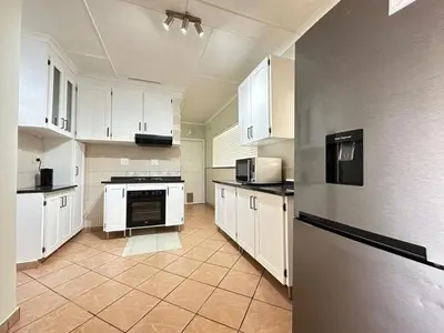a large kitchen with white cabinets and a refrigerator at 3 Bedroom House in Nelspruit in Nelspruit