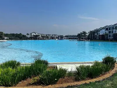 a large pool of blue water with buildings in the background at The Blyde Blue Lagoon 1 in Pretoria