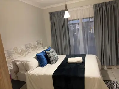 a bedroom with a large bed with blue pillows on it at The Blyde Blue Lagoon 1 in Pretoria