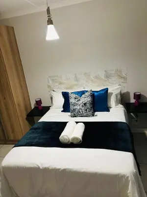 a bedroom with a large white bed with blue pillows at The Blyde Blue Lagoon 1 in Pretoria