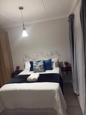 a bedroom with a large bed with blue and white pillows at The Blyde Blue Lagoon 1 in Pretoria