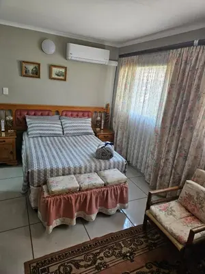 a bedroom with a bed and a chair and curtains at Luxury Meets Convenience Near City & Travel Links in Pretoria