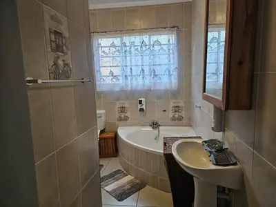 a bathroom with a tub and a sink and a window at Luxury Meets Convenience Near City & Travel Links in Pretoria