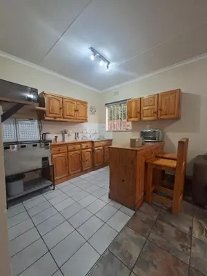 a large kitchen with wooden cabinets and a table at Stay at Wolkeberg in Middelburg