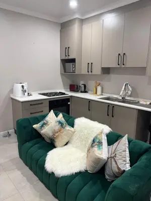 a green couch with pillows on it in a kitchen at Tranquil Stays in Polokwane
