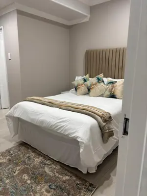 a bedroom with a bed with white sheets and pillows at Tranquil Stays in Polokwane