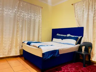a blue bed in a room with a window at Galaxy Guesthouse Pretoria North in Pretoria